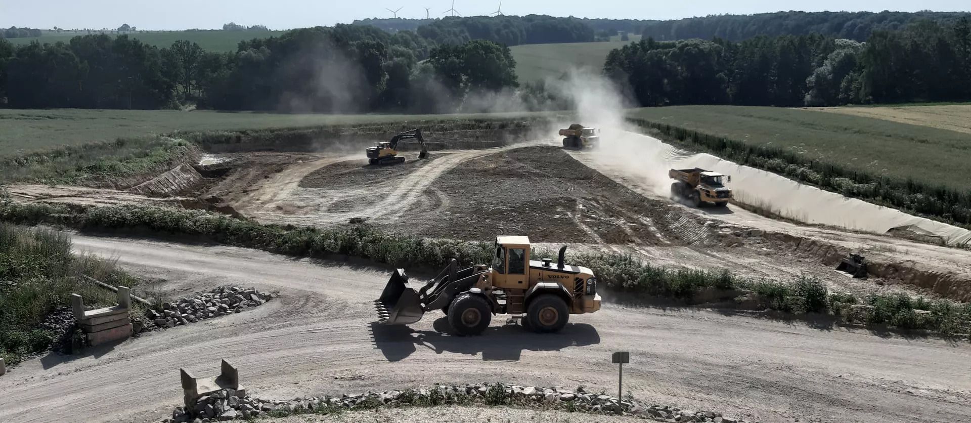 Radlader, Bagger und Dumper bei Erdarbeiten auf einer staubigen Großbaustelle im Freien